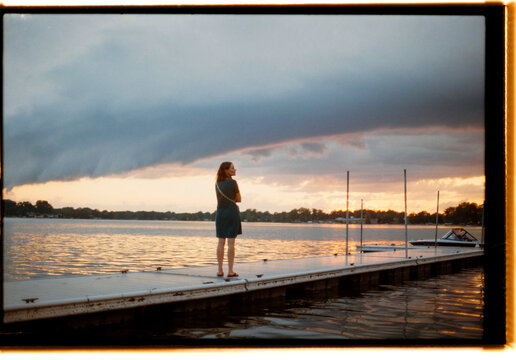 Woman Enjoying a Sunset by the Lake on a Calm Evening