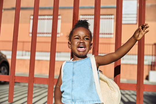 Little girl crying and waving goodbye on first day of school