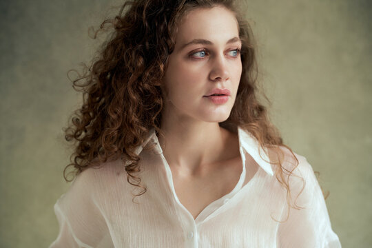 Woman with curly hair in white shirt posing indoors