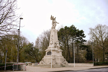 Obraz premium White memorial statue on pedestal at park roundabout under cloudy sky Calais France