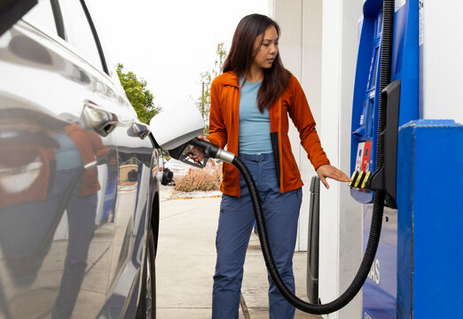Young Asian woman pumping gas pump at station 