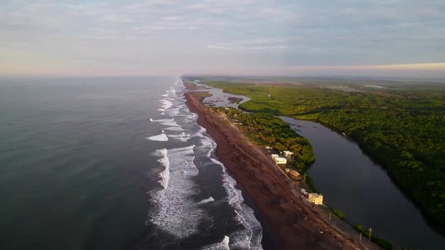 Drone zoom out revealing the coastline of Los Cristianos in Tenerife during golden sunset, with ocean waves and warm light reflecting on the sea.