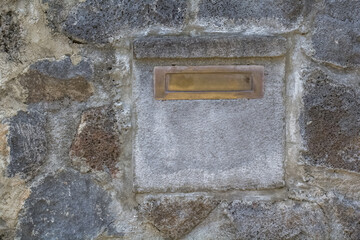 Bo&icirc;te aux lettres en pierre incrust&eacute;e dans un mur de cl&ocirc;ture 