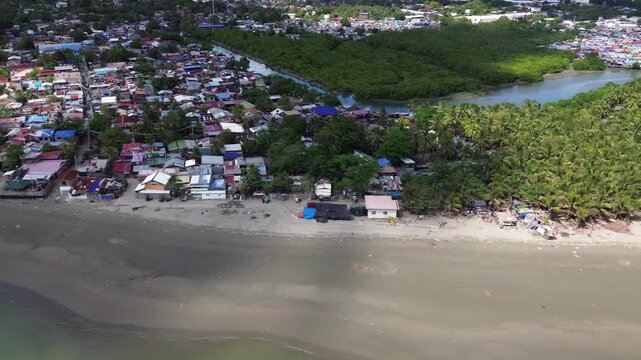 Aerial view of rural coastal neighborhood in Iloilo City Philippines featuring small houses near tropical shoreline. Authentic local community landscape along the urban edge of Panay Island.