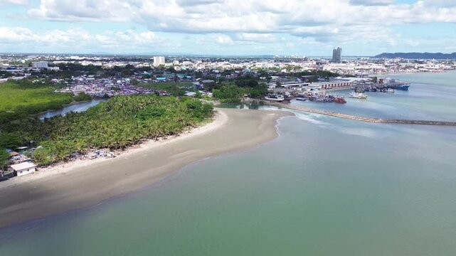 Aerial cityscape of Iloilo City Philippines showing expanding residential districts and tropical coastline under bright clouds. Dynamic urban growth and coastal development on Panay Island.