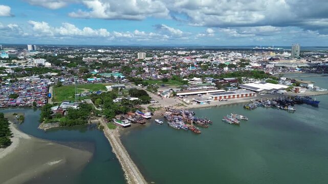 Aerial view of Iloilo City showing tropical coastline and urban skyline under dramatic clouds. Harbor with Anchored Boats, Coastal development and vibrant Philippine city atmosphere from above.