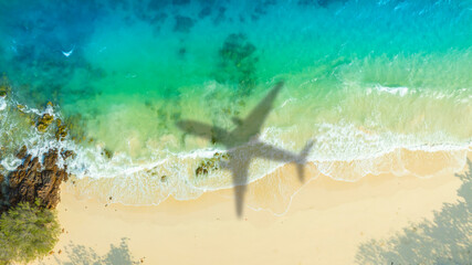 Aerial view of shadow passenger plane silhouette and sandy beach blue sea with waves at sea beach...