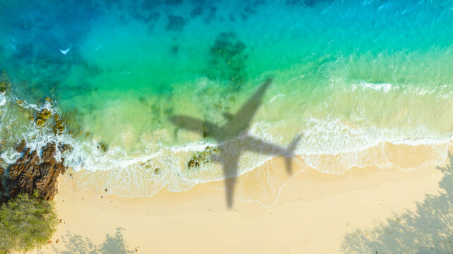 Aerial view of shadow passenger plane silhouette and sandy beach blue sea with waves at sea beach summer vacation sea travel concept	
