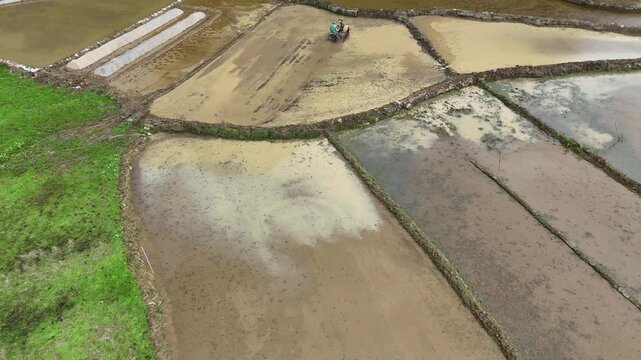 A Farmer Driving a Tractor in Muddy Karst Water Fields at Dawn, Spring Plowing, Guangxi
