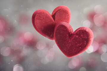 Obraz premium Two red hearts are floating in the air with a bokeh background