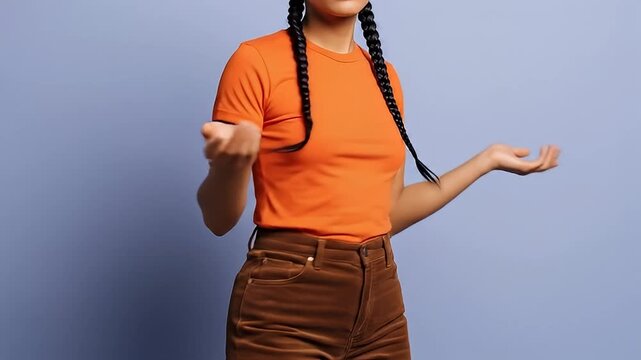 Young woman in orange t-shirt and brown corduroy pants shrugging her shoulders