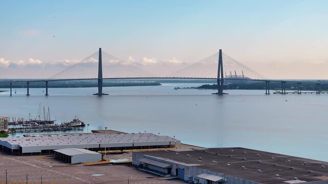 Aerial view of Arthur Ravenel Jr. Bridge in downtown Charleston, South Carolina skyline cityscape landscape with bay water and city port buildings during morning sunrise light - 4K Drone