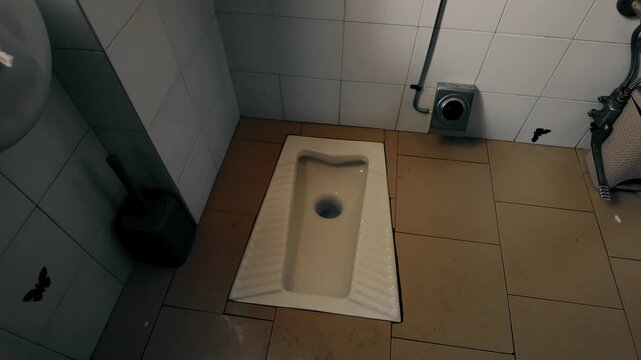 Traditional squat toilet fixture installed in tiled floor of public restroom in Italy