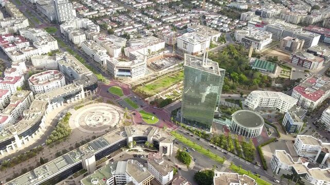Aerial shot highlighting the circular urban layout of Mahaj Riad plaza. Features modern curved office buildings, green avenues, and corporate infrastructure in Rabat's business hub.