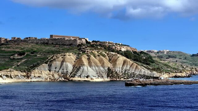 Scenic Summer View of Fort Chambray Overlooking Steep Clay Cliffs in Gozo Malta During Sunny Weather Featuring Earthy Tones and Deep Blue Sea Captured from a Low Angle Boat Perspective on the Water