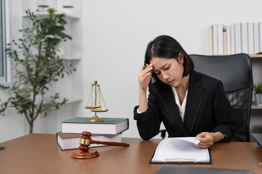 Stressed Female Lawyer Reviewing Case Files. female attorney appears stressed while reviewing legal documents