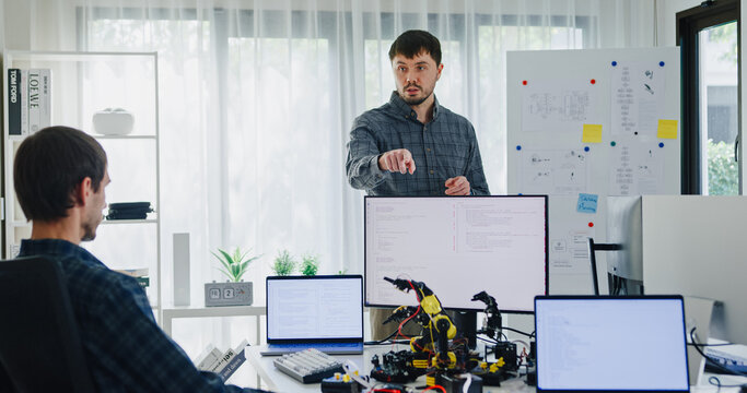 Team adult male engineer develop present AI robotics hand project at tech workspace. Artificial intelligence, collaboration support prototype development, robotic, debugging, machine learn, training.