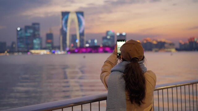 Young woman tourist taking pictures of the landmark building at Jinji Lake in Suzhou, China