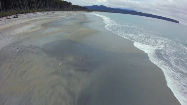 Cinematic FPV drone flying fast above untouched sandy beach in Bruce Bay, New Zealand
