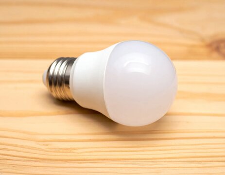 Energy-Efficient LED Light Bulb on a Warm Wooden Surface.