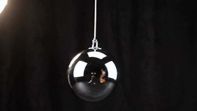 Polished, oval-shaped object suspended against a dark, textured background