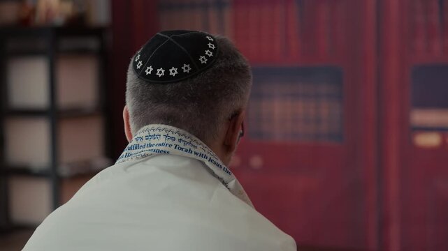 POV of Jewish Men from the back, covering a traditional Jewish Tallit blue and gold stripes and tassels. Praying