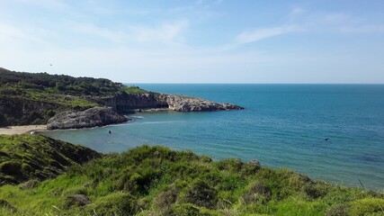 Scenic coastal bay with turquoise water and rocky cliffs on Black Sea coast. Peaceful cove with green hills and sandy beach in Turkey.
