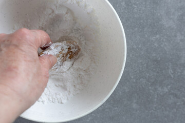 coating vanilla crescent cookie in powdered sugar by hand
