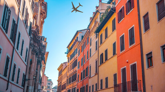 Passenger airplane flying over a narrow ancient street in Rome, Italy.