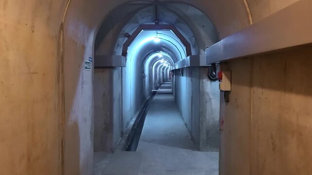 Inspection and maintenance gallery inside the dam. Underground maintenance area, lighting, movement sensors, electrical wiring conduits, and seepage water collection area. Spain.
