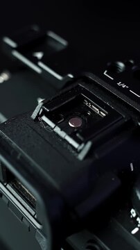 Top view macro of mirrorless camera hot shoe mount, electronic viewfinder and mode dial in moody studio lighting with shallow depth of field. vertical