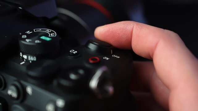 Close-up of hand sliding a mirrorless camera power switch to OFF, showing mode dial and controls in soft studio lighting with shallow depth of field.