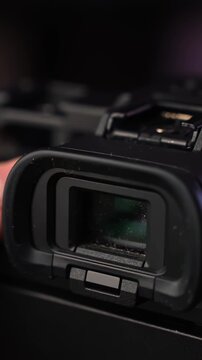 Close-up of mirrorless camera electronic viewfinder eyepiece with dust particles, cinematic macro shot of photography gear details. Vertical shot.