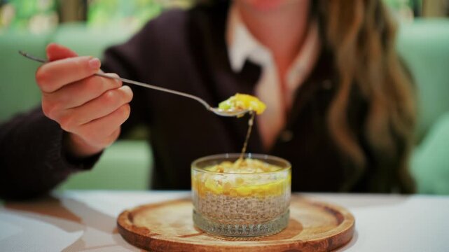 Woman eating a chia pudding in a glass cup using a spoon