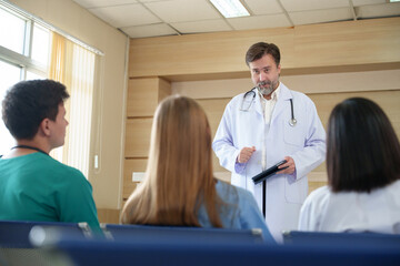 Obraz premium Senior male doctor leading medical team meeting in hospital seminar room