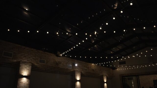 Atmospheric wedding venue setup with elegant table settings, glowing candles, and decorative lanterns creating a warm and romantic ambiance. Beautiful reception d cor prepared for guests, cozy evening