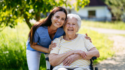 Home nurse taking care of elderly woman in wheelchair.