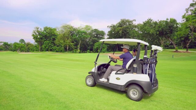 Asian golfer team ride in golf cart together on a scenic golf course.