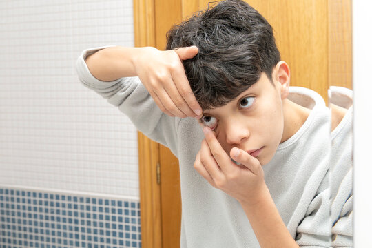Teenager boy learning to insert contact lens, managing vision correction