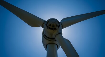 Low-angle close-up of a wind turbine against a bright blue sky