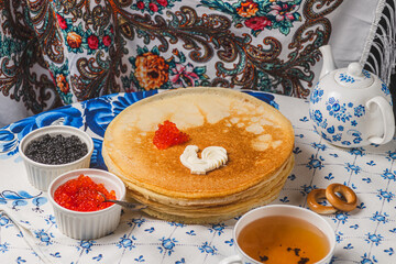 Pancakes on the table next to the samovar and caviar