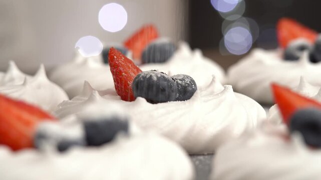 Close up of vanilla dessert meringue with fresh berries is sprinkled with powdered sugar. Cake with blueberries and strawberries. Bakery confectionery