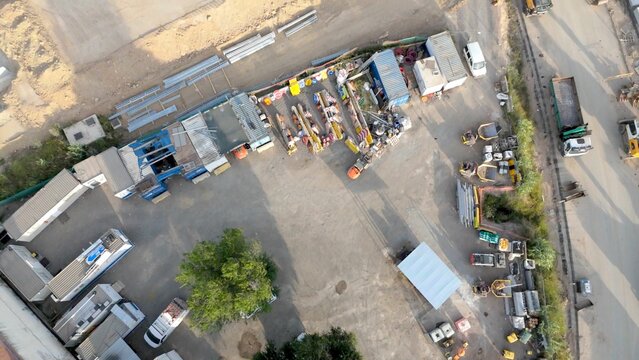 Industrial construction site from above showing machinery, storage containers and workers engaged in infrastructure development at an organized outdoor work area