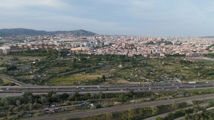 Obraz premium Barcelona cityscape view from tibidabo hills, showing urban landscape spreading towards the mountains with a busy highway and train tracks
