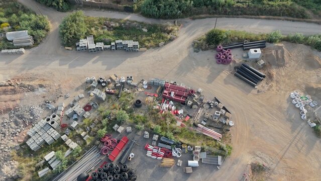 Industrial construction site seen from aerial top view showing varied building materials including pipes. Concrete blocks. Steel beams. And rubble