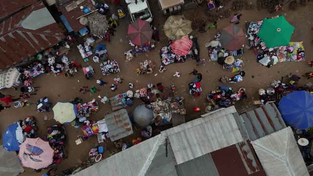 Top-down drone shot of the vibrant outdoor market in Fumso, Ghana. Aerial view of colorful stalls, people, and daily village life. West African culture and commerce