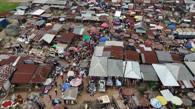 Drone footage capturing the dense rooftops and busy activity of a traditional outdoor market of Fumso, Ghana. Aerial perspective of West African community life and local commerce