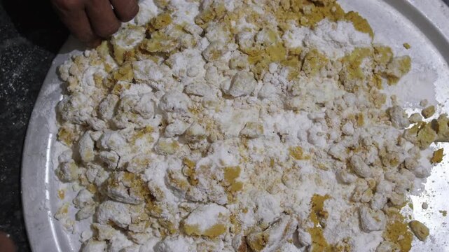 A detailed close-up of the traditional mixing process for Indian Besan Ladoo featuring roasted gram flour and assorted nuts.