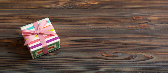 Obraz premium wrapped Christmas or other holiday handmade gift box in color paper with ribbon on colored background. Present box, decoration of gift on colored table, top view with copy space