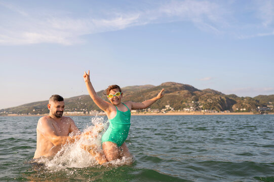 Father throwing daughter into sea water.